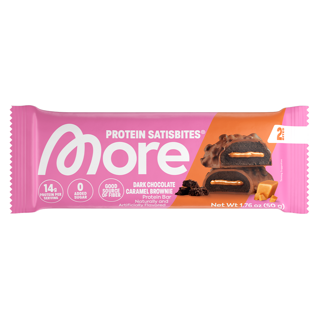 A packaged protein satiskbite bar in a pink wrapper with an orange diagonal section, showing the More brand logo and a photo of a dark chocolate caramel brownie piece on the front.